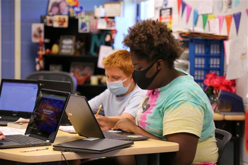 Students work during class at their desk with laptops